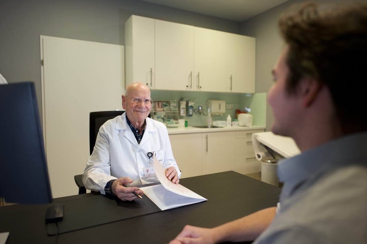 Arzt im Beratungsgespräch mit einem Patienten am Ordinationsschreibtisch